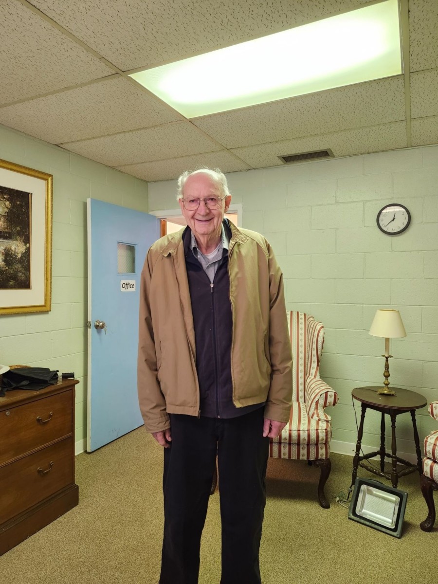 An old person standing in a room

Description automatically generated
